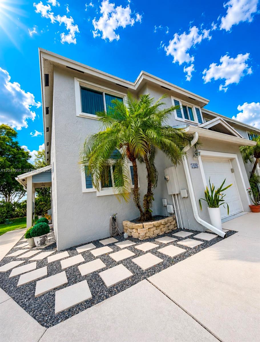 A two-story gray house features a palm tree, stone planter, and a paved walkway — 1428 SW 47th Ave, Deerfield Beach FL 33442, DEERFIELD BEACH, FL