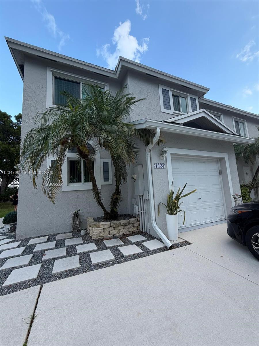 A two-story gray house features a palm tree, stone planter, and a single-car garage — 1428 SW 47th Ave, Deerfield Beach FL 33442, DEERFIELD BEACH, FL