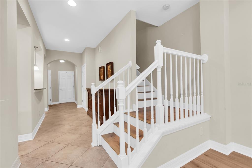 A foyer with tile flooring features a white staircase with wood treads and a railing — 12670 SILVERDALE STREET, TAMPA, FL