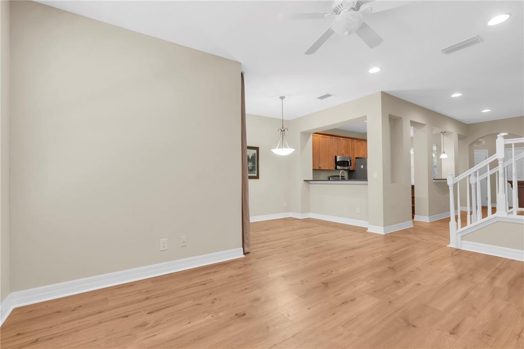 A bright, open-concept living area features light wood-look flooring, beige walls, and a kitchen pass-through — 12670 SILVERDALE STREET, TAMPA, FL