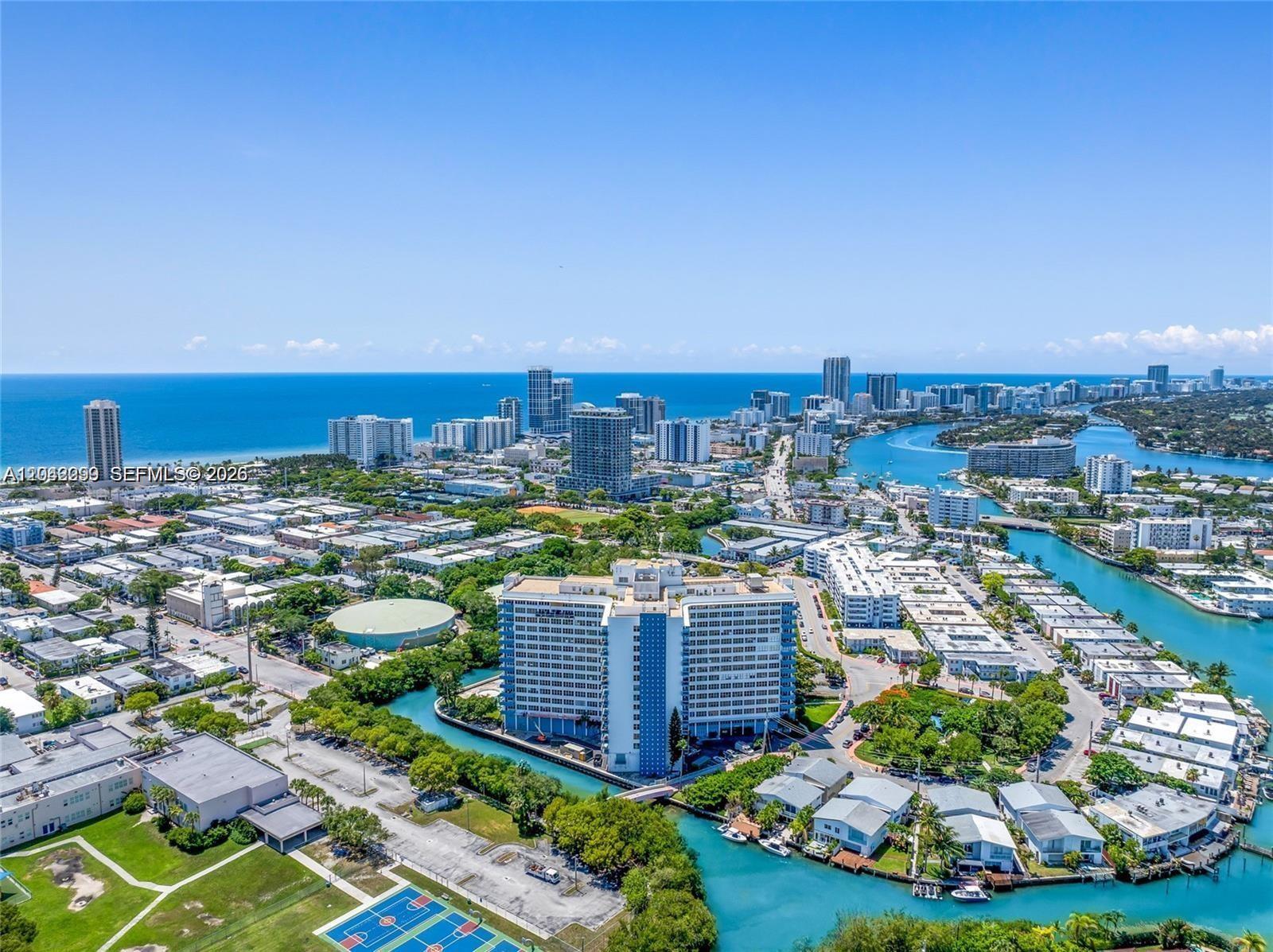 An aerial view shows a coastal city with a large apartment building surrounded by water — 7441 Wayne Ave # 15i, Miami Beach FL 33141, MIAMI BEACH, FL