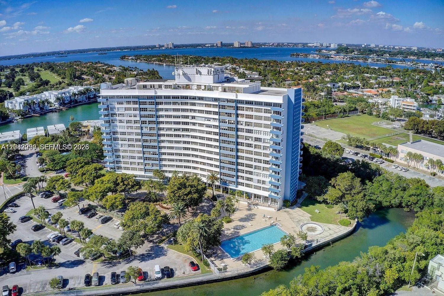 An aerial view shows a tall, curved residential building with a pool and parking lot — 7441 Wayne Ave # 15i, Miami Beach FL 33141, MIAMI BEACH, FL