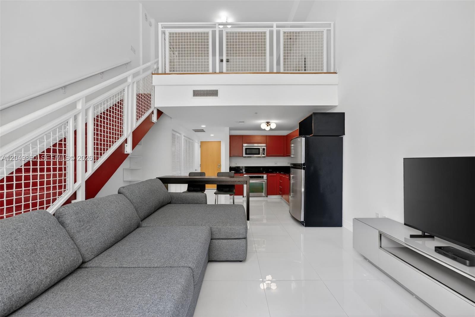 A living room with a gray sectional sofa, a kitchen with red cabinets, and a loft — 253 NE 2nd St # 424, Miami FL 33132, MIAMI, FL