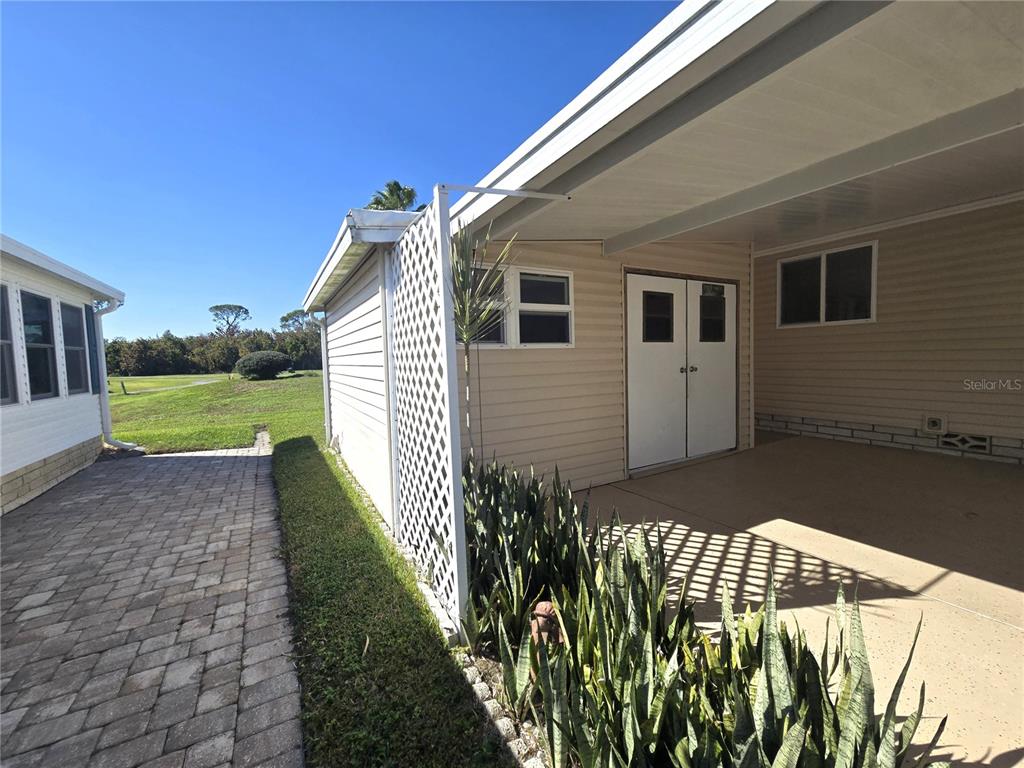 A paved walkway leads to a covered patio area with a storage shed and lattice screen — 43 LEOPOLD LANE, HAINES CITY, FL