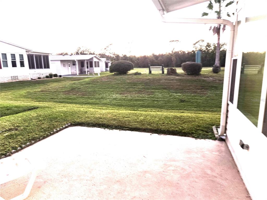 A concrete patio overlooks a grassy yard with a small hill and neighboring houses — 43 LEOPOLD LANE, HAINES CITY, FL