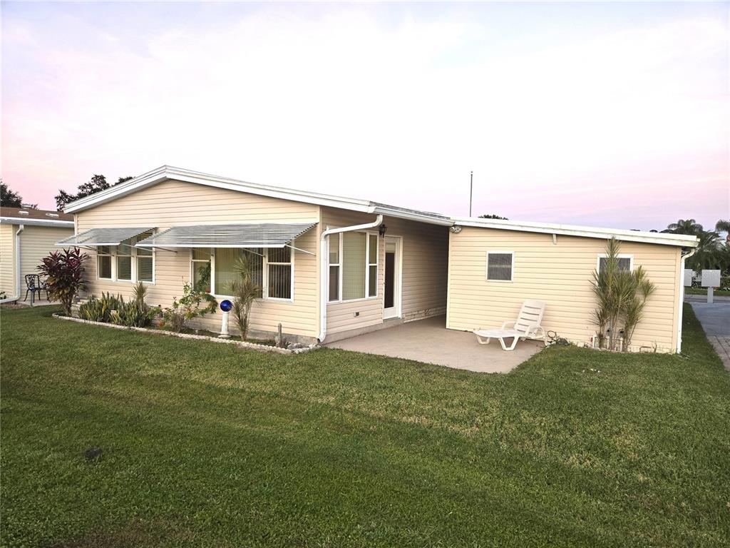 A single-story house with beige siding, metal window awnings, and a concrete patio area — 43 LEOPOLD LANE, HAINES CITY, FL