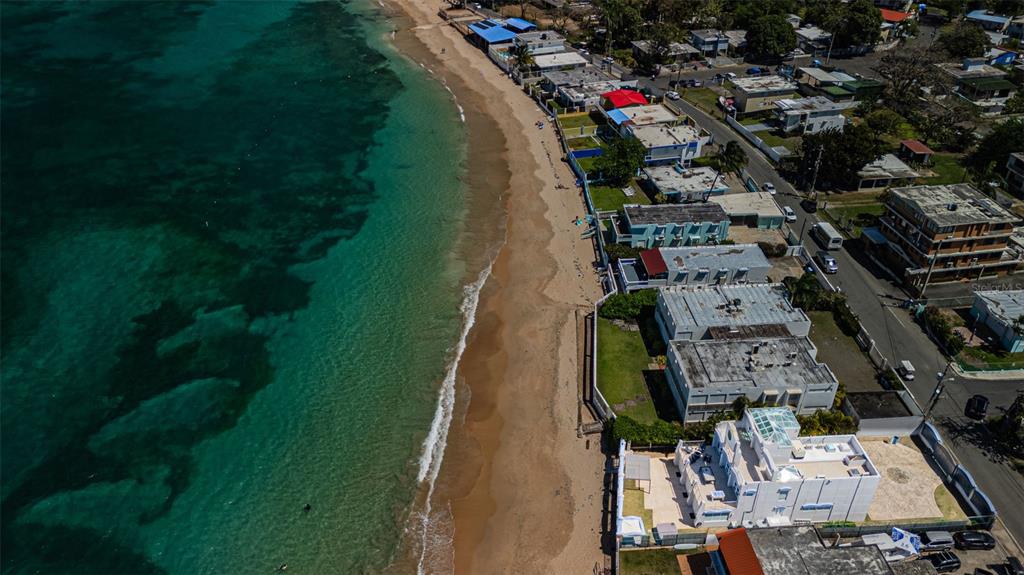 An aerial view shows a sandy beach bordering the ocean next to several coastal buildings — Carr. 690 LOTE #5 BO. CERRO GORDO, VEGA ALTA, PR