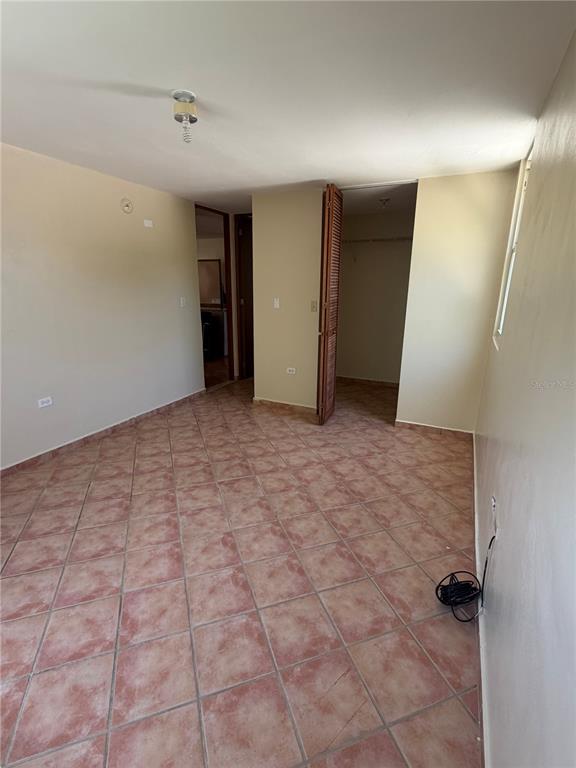 An empty bedroom features tan walls, tiled flooring, and a closet with louvered doors — 6690 COND. COVE BY THE SEA UNIT C-201, VEGA ALTA, PR