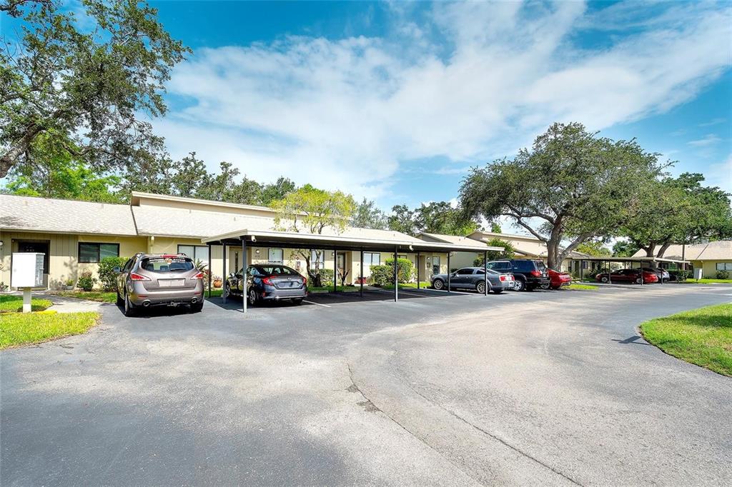 A parking lot with covered carports sits in front of single-story apartment buildings — 6024 28TH STREET W, BRADENTON, FL