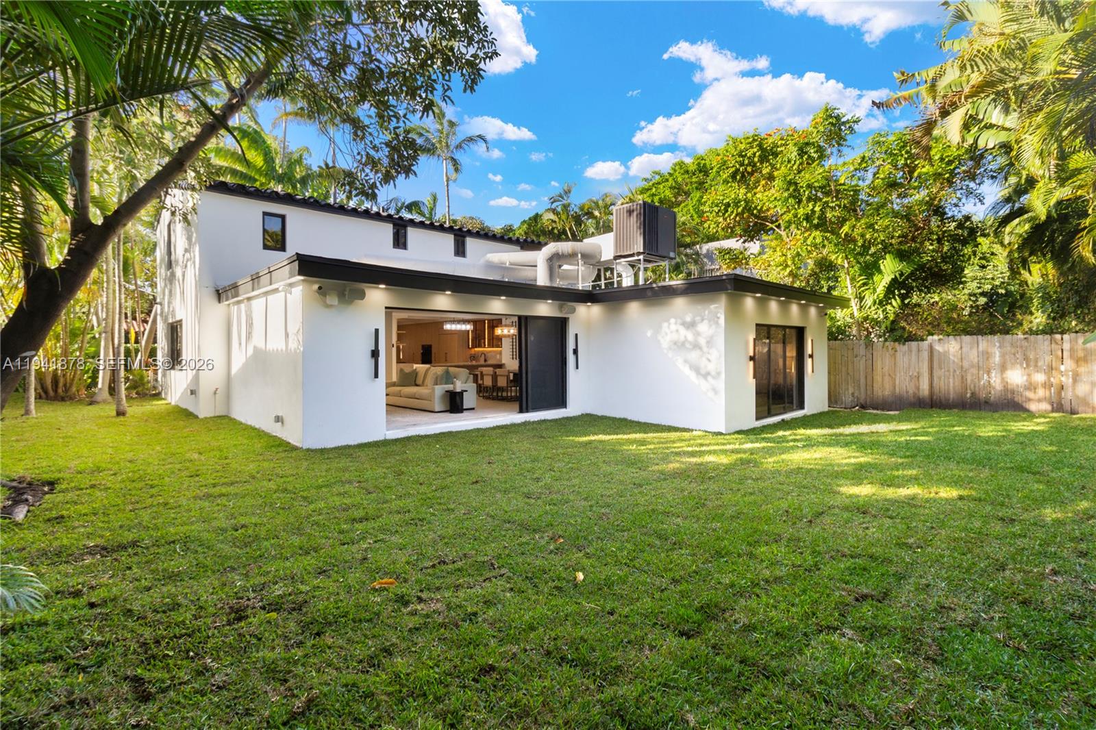 The exterior of a white house features a large grassy backyard and sliding glass doors — 435 W 43rd St, Miami Beach FL 33140, MIAMI BEACH, FL