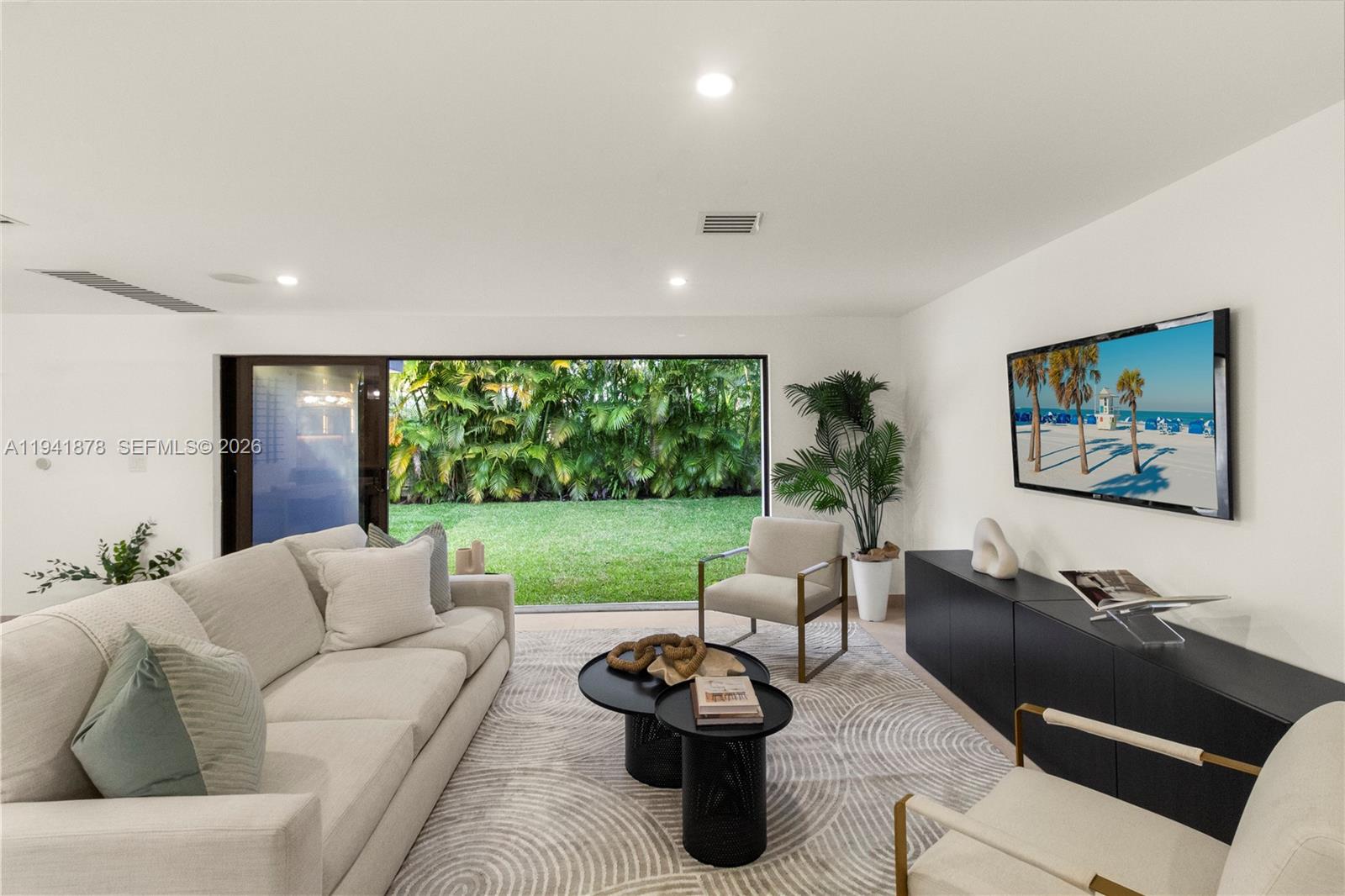 A living room features a light-colored sofa, two armchairs, nested coffee tables, and a television — 435 W 43rd St, Miami Beach FL 33140, MIAMI BEACH, FL