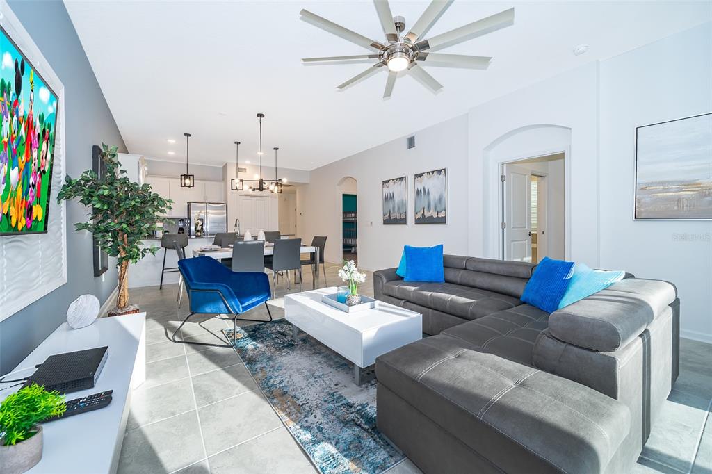 A living room with a grey sectional sofa, blue accent chair, and an open kitchen — 8863 CABOT CLIFFS DRIVE UNIT 101, DAVENPORT, FL