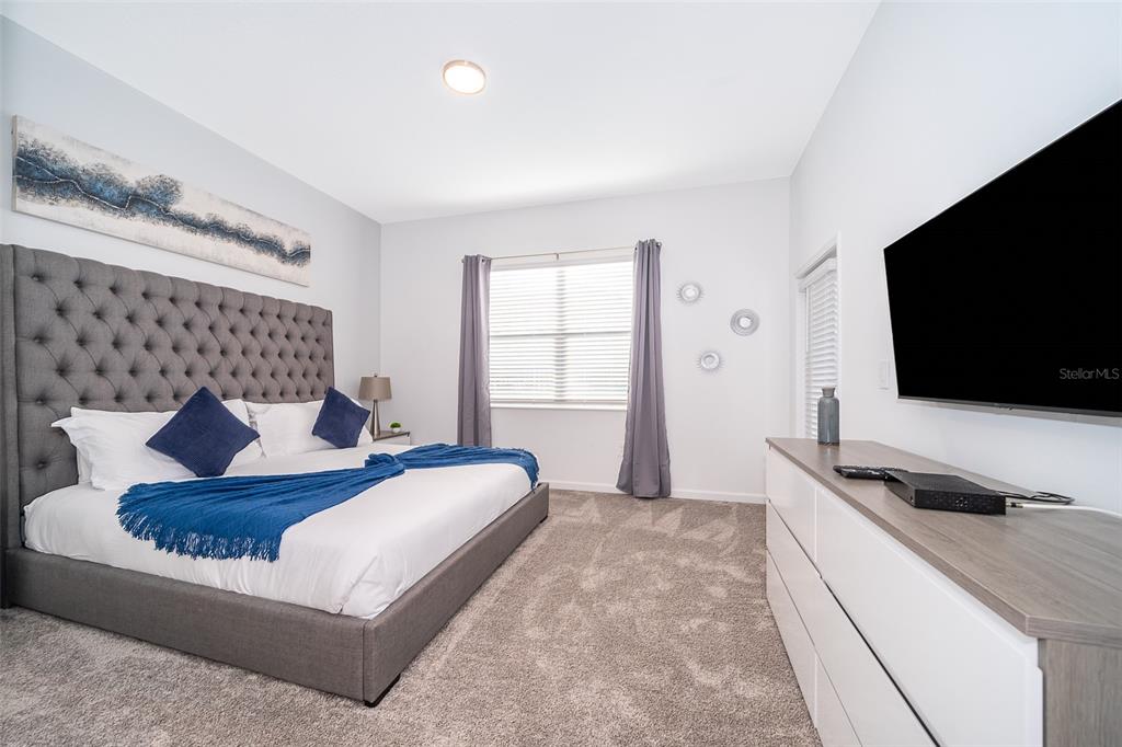 A bedroom features a tufted gray headboard, white bedding with blue accents, and a dresser — 8863 CABOT CLIFFS DRIVE UNIT 101, DAVENPORT, FL