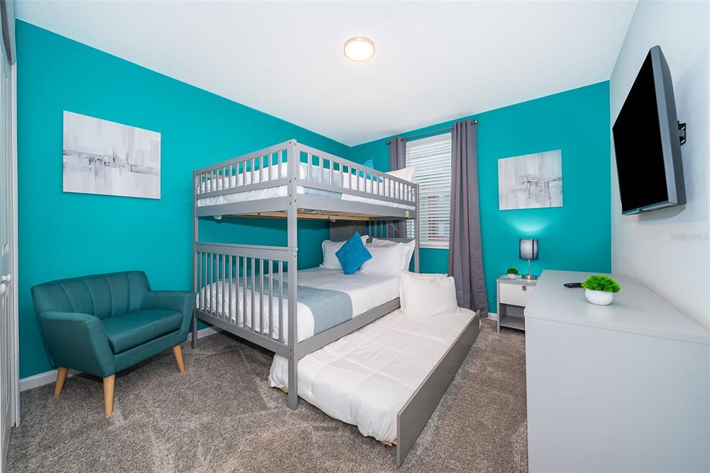 A bedroom features a gray bunk bed with a trundle, teal walls, and a gray armchair — 8863 CABOT CLIFFS DRIVE UNIT 101, DAVENPORT, FL