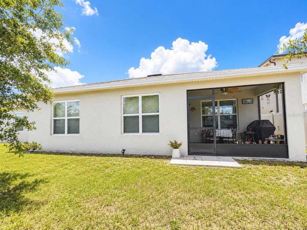 The exterior of a house features a beige stucco wall, two windows, and a screened-in patio — 157 HENRY STEVENS DRIVE, HAINES CITY, FL