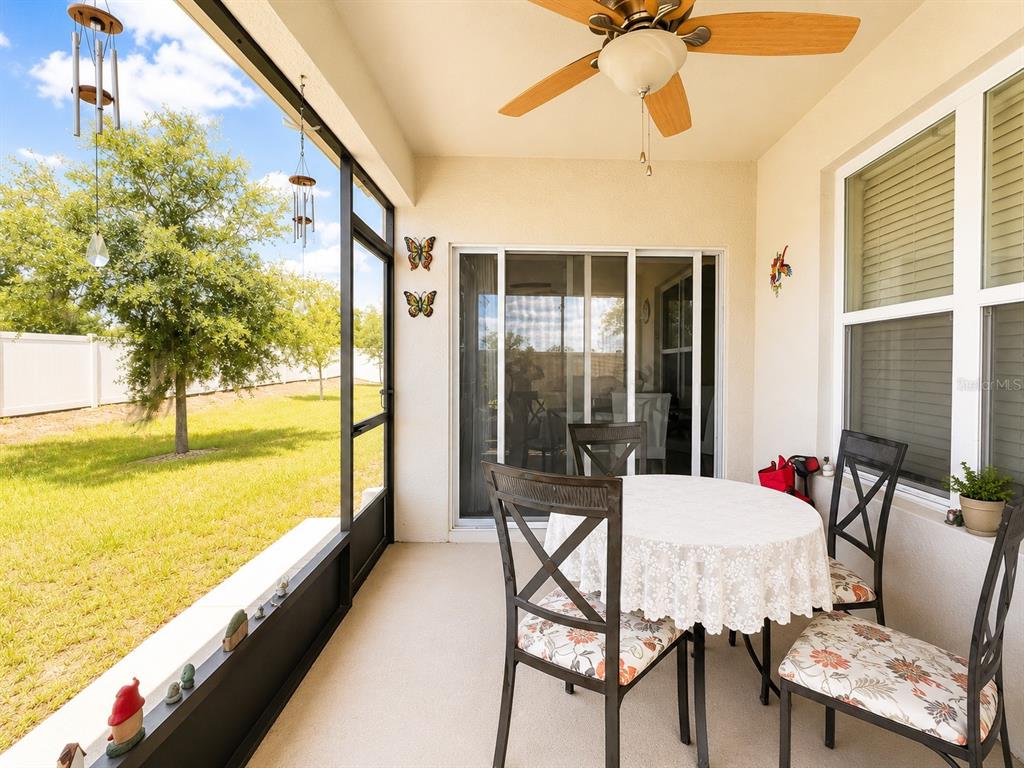 A screened-in patio features a dining set, a ceiling fan, and views of a backyard — 157 HENRY STEVENS DRIVE, HAINES CITY, FL