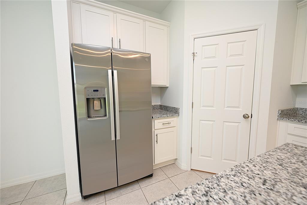 A kitchen features a stainless steel refrigerator, white cabinets, and granite countertops — 685 CROWN ROSE DRIVE, EAGLE LAKE, FL