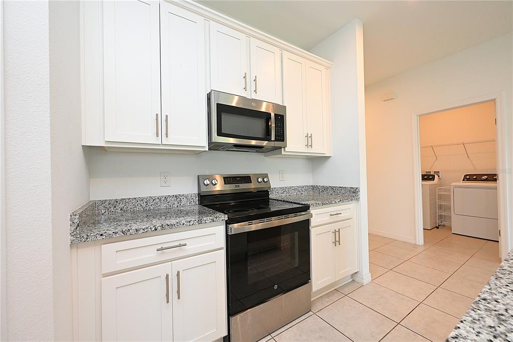 A kitchen with white cabinets, granite countertops, stainless steel appliances, and tile flooring — 685 CROWN ROSE DRIVE, EAGLE LAKE, FL