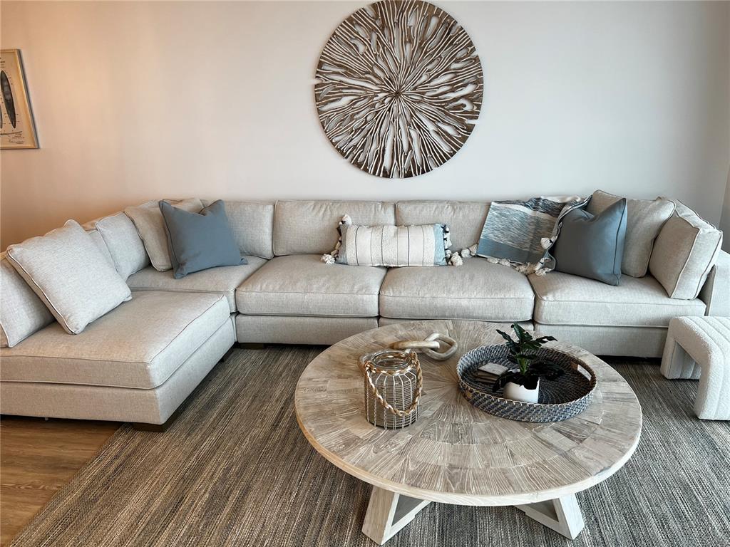 A living room features a large beige sectional sofa, a round wooden coffee table, and wall decor — 1465 GULF OF MEXICO DRIVE UNIT 504, LONGBOAT KEY, FL