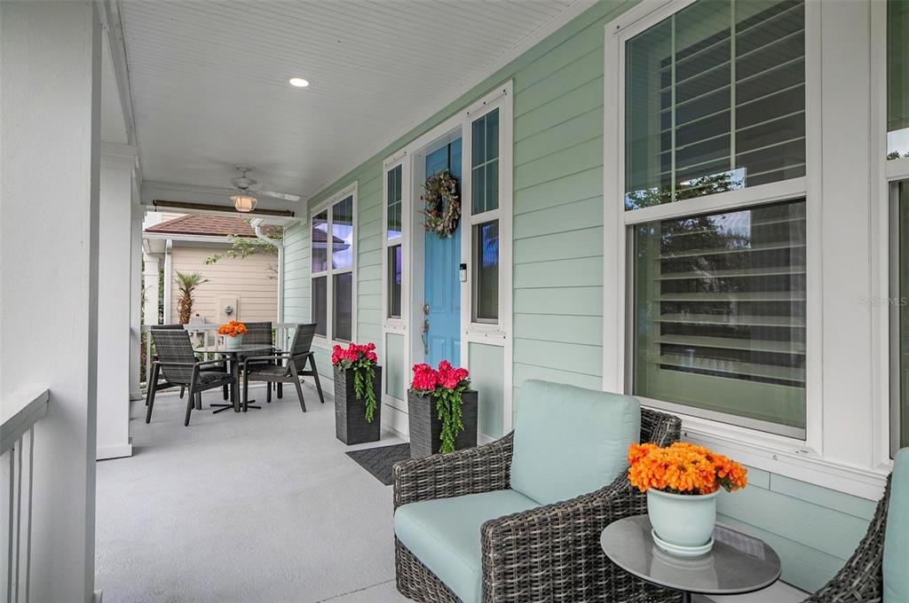 A covered front porch features light green siding, a blue door, and outdoor wicker furniture — 35 HIDDEN TREASURE DRIVE, PALM COAST, FL