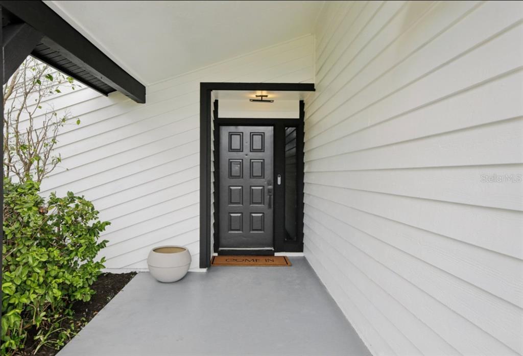 A front entryway features a black door with a side light and white siding — 665 EASTPOINTE PARKWAY, SARASOTA, FL