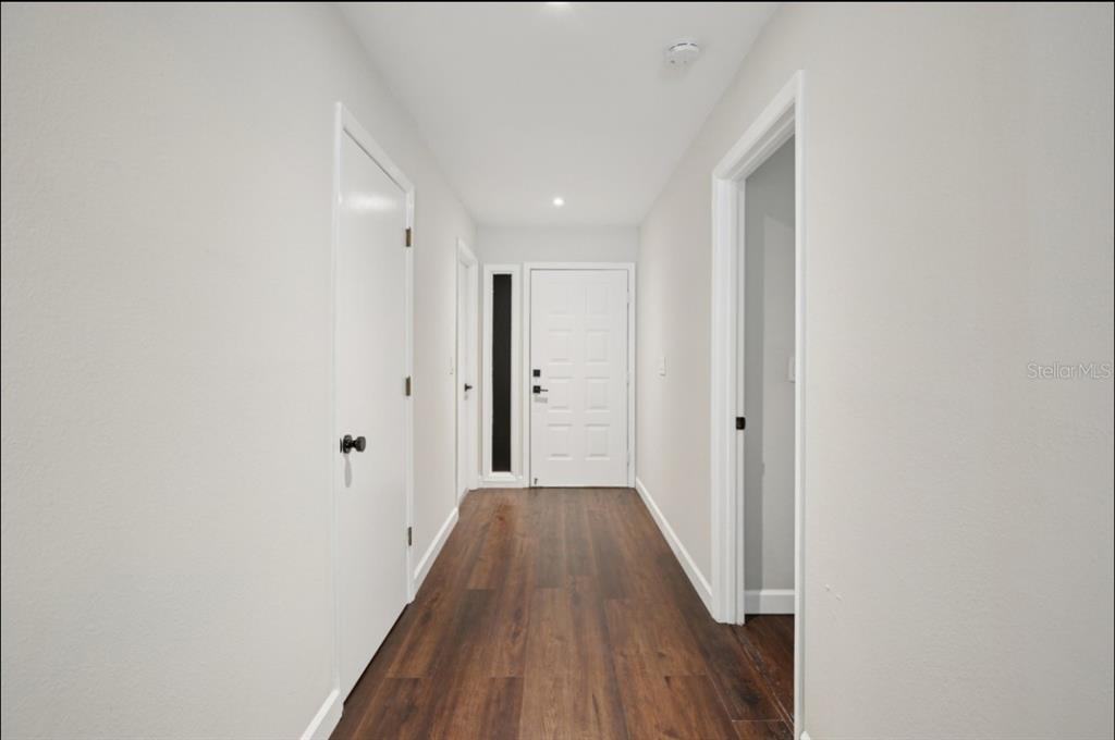 A hallway with wood-look flooring, white walls, and doors leading to other rooms — 665 EASTPOINTE PARKWAY, SARASOTA, FL
