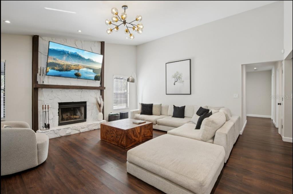 A living room features a white stone fireplace, a large sectional sofa, and wood flooring — 665 EASTPOINTE PARKWAY, SARASOTA, FL