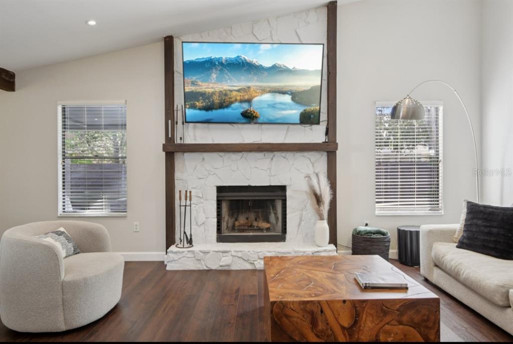 A living room features a white stone fireplace with a mounted television and wood mantel — 665 EASTPOINTE PARKWAY, SARASOTA, FL