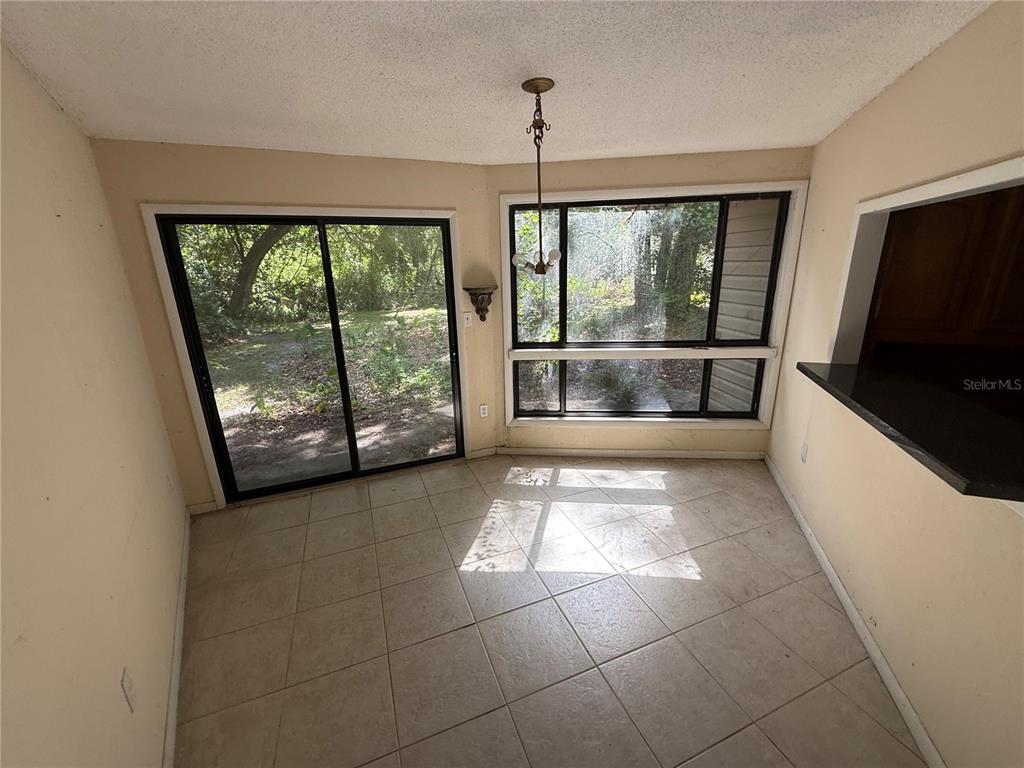 A dining area features tile flooring, a sliding glass door, and a large window — 6904 PINETREE LANE E, LAKELAND, FL