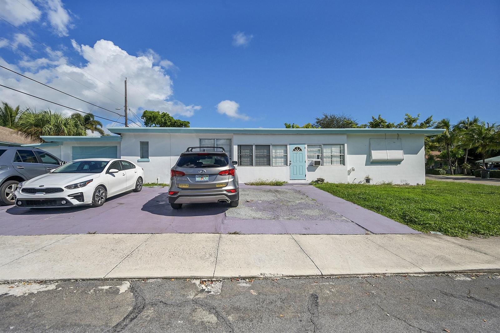 A single-story white house with a light blue door and a purple-painted concrete driveway — 721 N A Street, FL 33460, FL