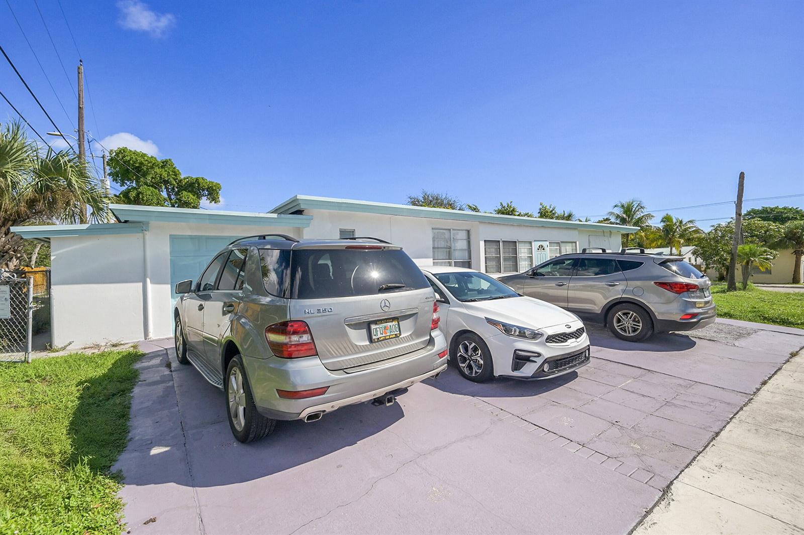 Three cars are parked in the driveway in front of a single-story white house — 721 N A Street, FL 33460, FL