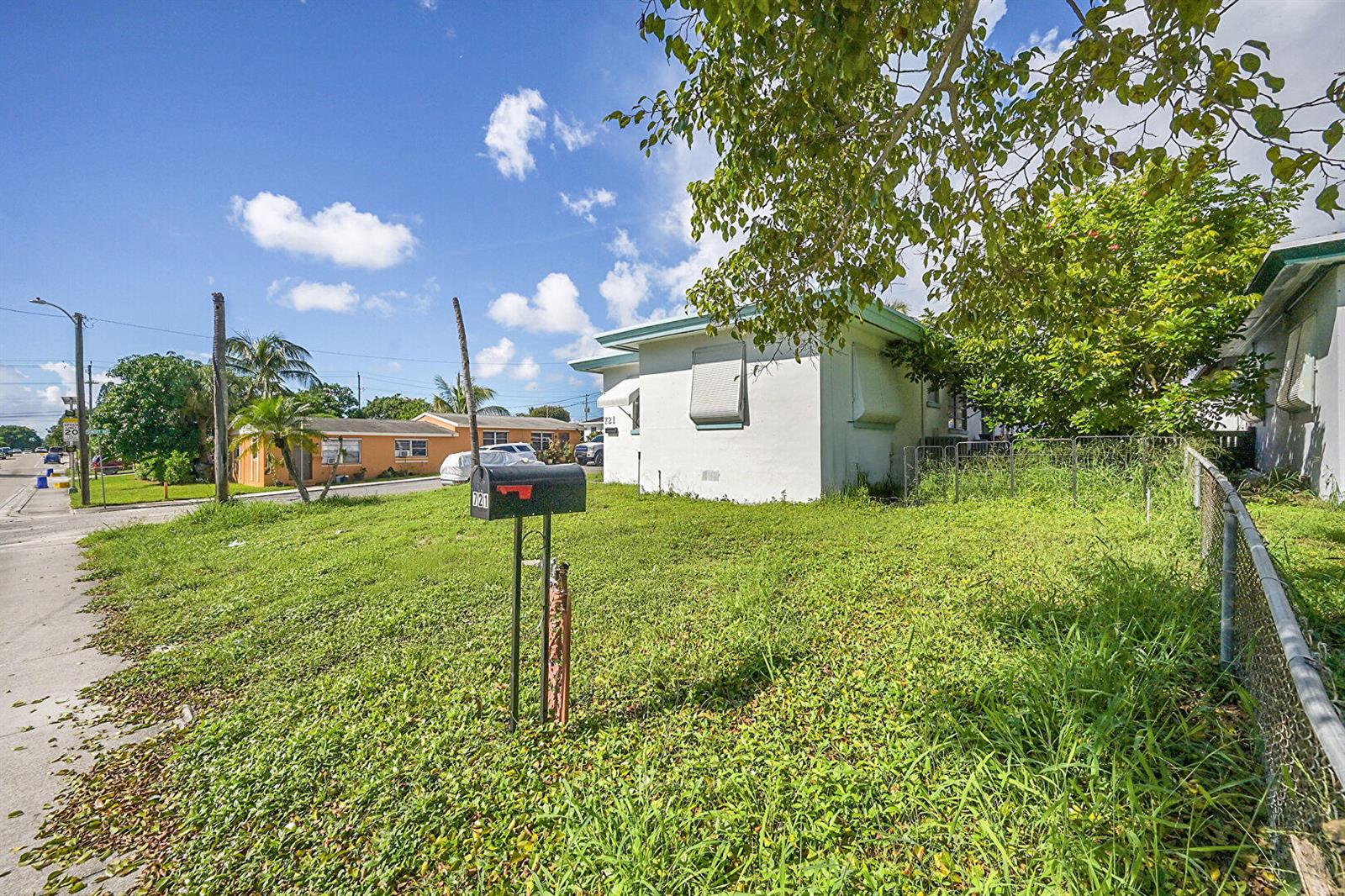 A white single-story house with a grassy yard and a mailbox stands under a blue sky — 721 N A Street, FL 33460, FL