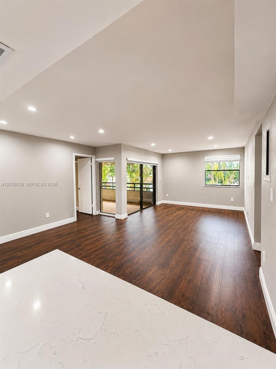 An open-concept living area features dark wood-look flooring, recessed lighting, and a sliding glass door — 20005 NE 3rd Ct # 8, Miami FL 33179, MIAMI, FL