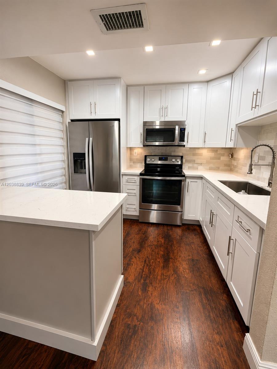 A kitchen features white cabinets, stainless steel appliances, quartz countertops, and dark wood flooring — 20005 NE 3rd Ct # 8, Miami FL 33179, MIAMI, FL