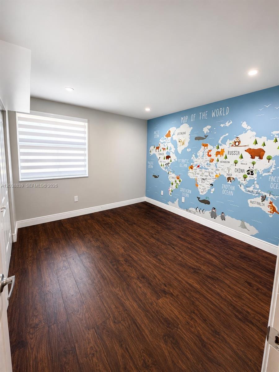 A bedroom features dark wood-look flooring, light gray walls, and a large world map mural — 20005 NE 3rd Ct # 8, Miami FL 33179, MIAMI, FL
