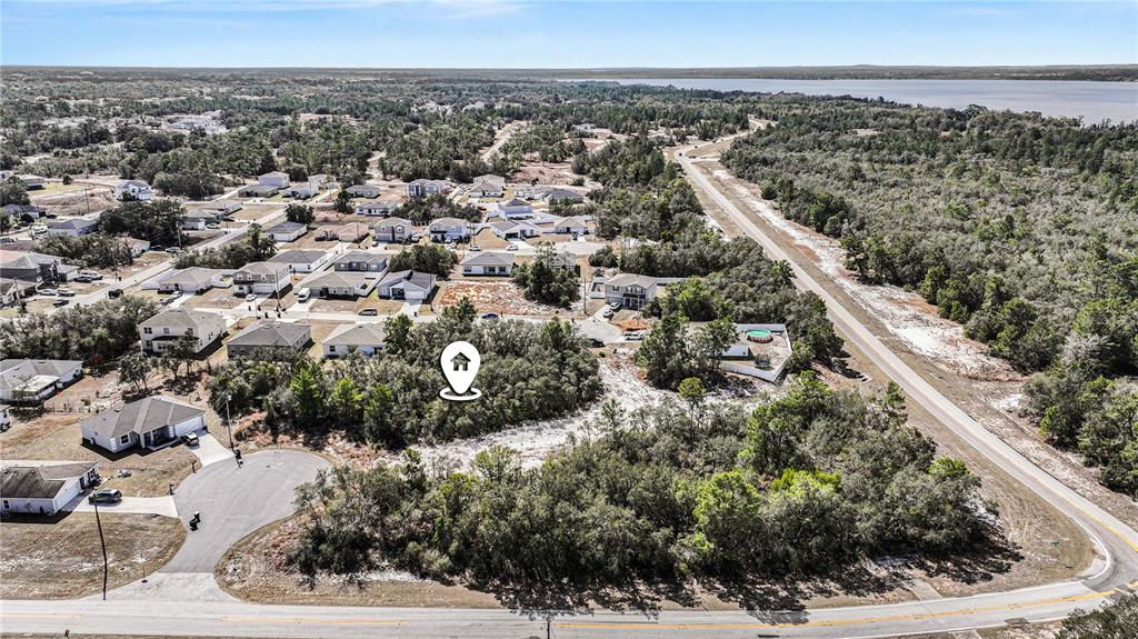 An aerial view shows a vacant wooded lot situated within a residential neighborhood — 1204 WAVERLY PLACE, POINCIANA, FL
