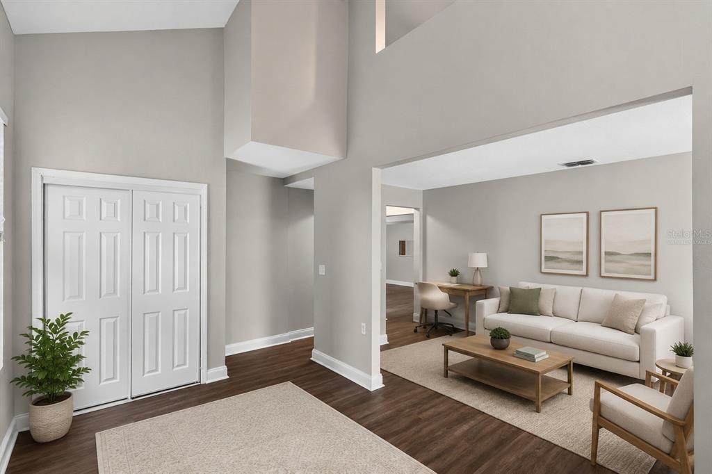 A bright entryway with wood floors leads into a living room with a white sofa — 3918 PINE BREEZE ROAD S, JACKSONVILLE, FL