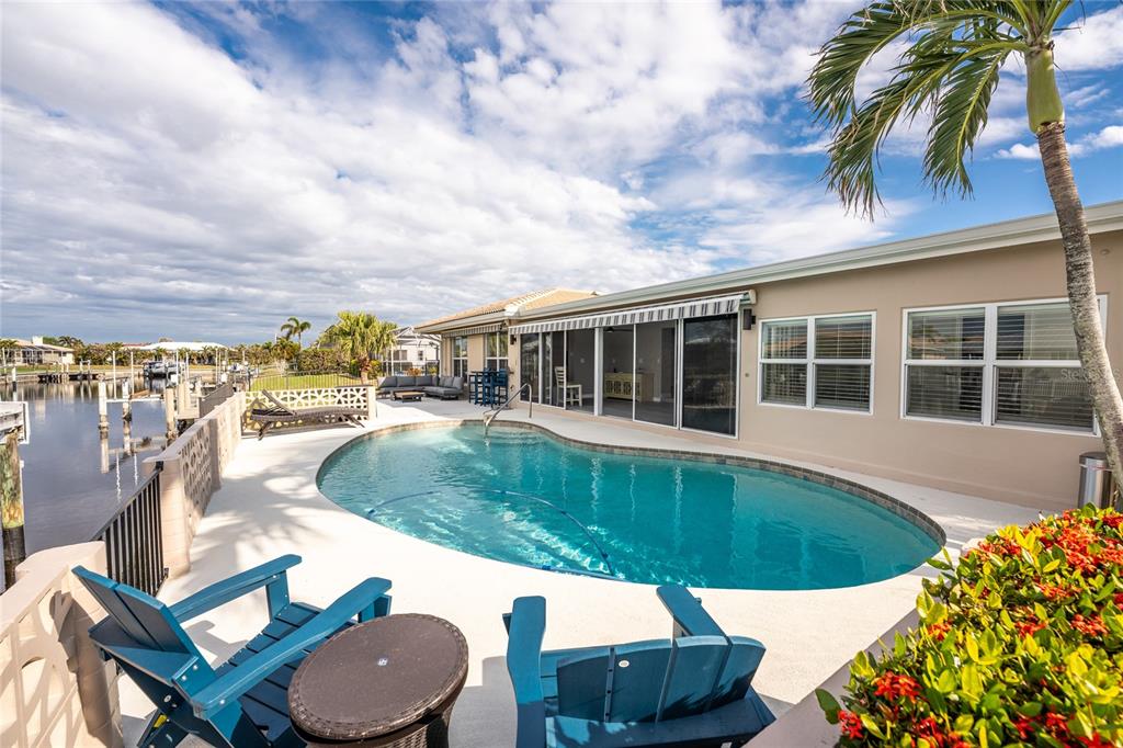 A backyard pool area features a kidney-shaped pool, patio furniture, and a view of the canal — 951 LASSINO COURT, PUNTA GORDA, FL