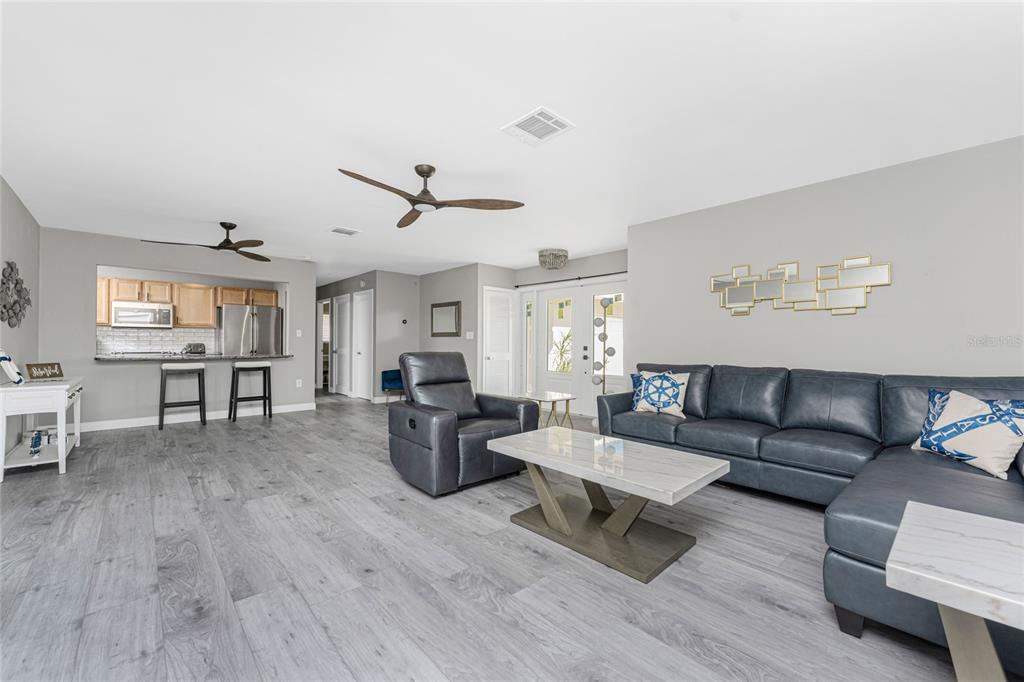 A living room features gray wood-look flooring, a blue sectional, and an open kitchen — 951 LASSINO COURT, PUNTA GORDA, FL