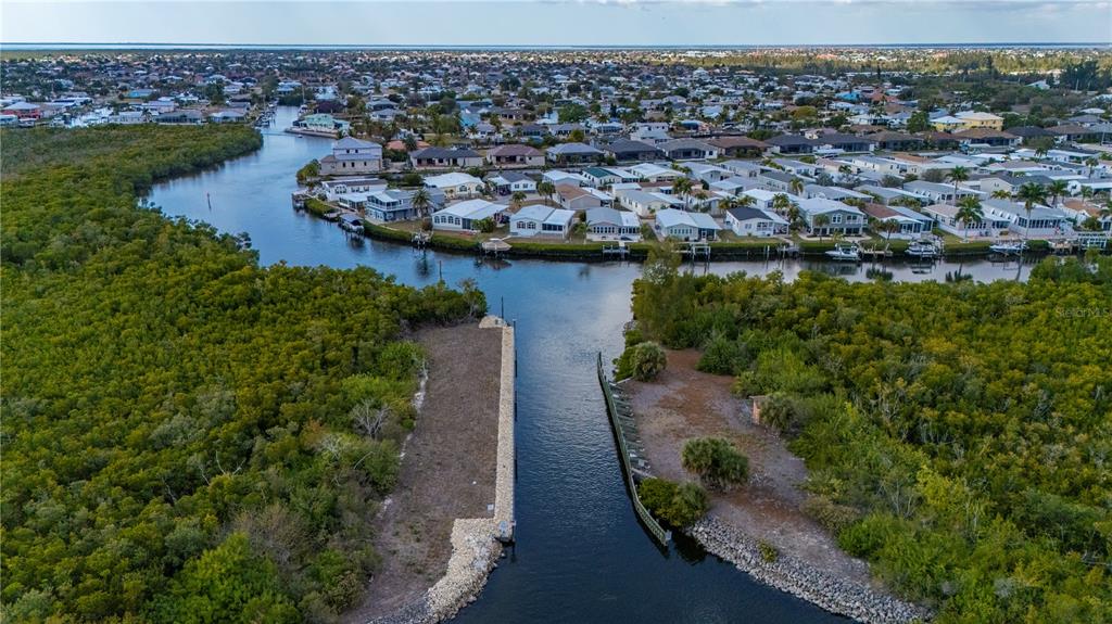 An aerial view shows a narrow canal leading toward a residential neighborhood surrounded by mangroves — 3731 CANDIA DRIVE, PUNTA GORDA, FL