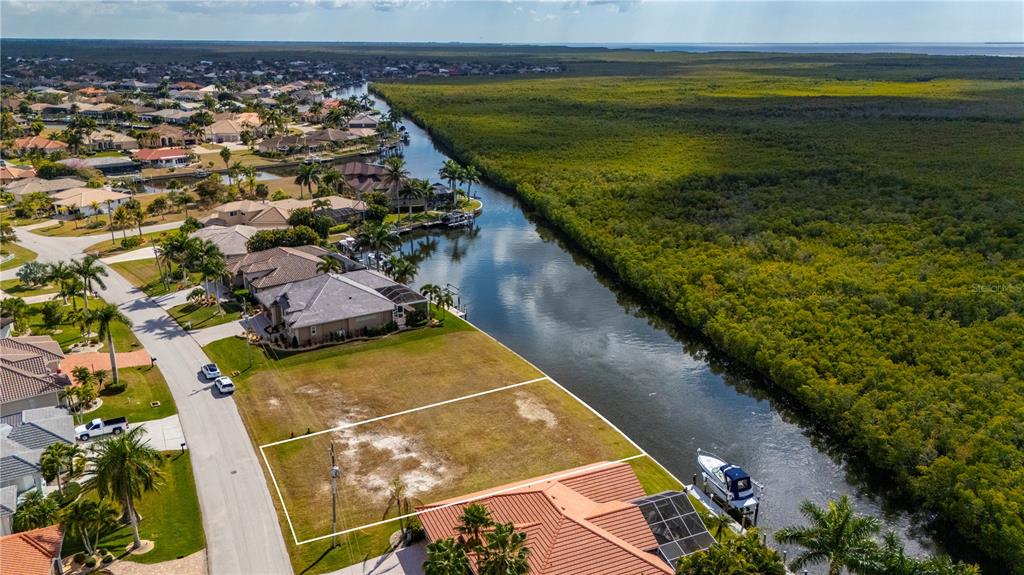 An aerial view shows a vacant waterfront lot bordered by a canal and mangroves — 3731 CANDIA DRIVE, PUNTA GORDA, FL