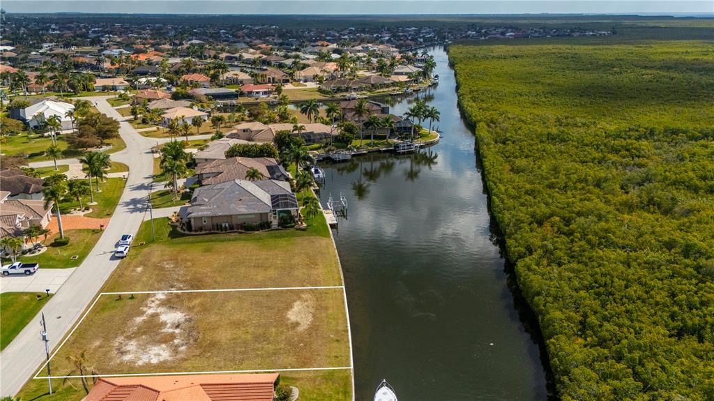 An aerial view shows a vacant waterfront lot bordered by a canal and mangroves — 3731 CANDIA DRIVE, PUNTA GORDA, FL