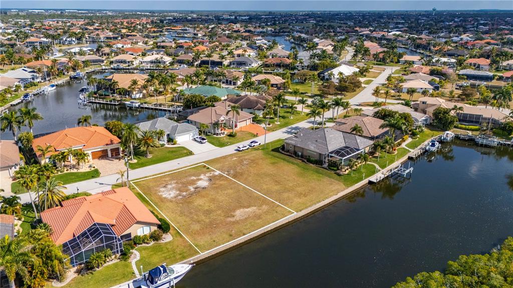 An aerial view shows a vacant waterfront lot situated between two houses along a canal — 3731 CANDIA DRIVE, PUNTA GORDA, FL