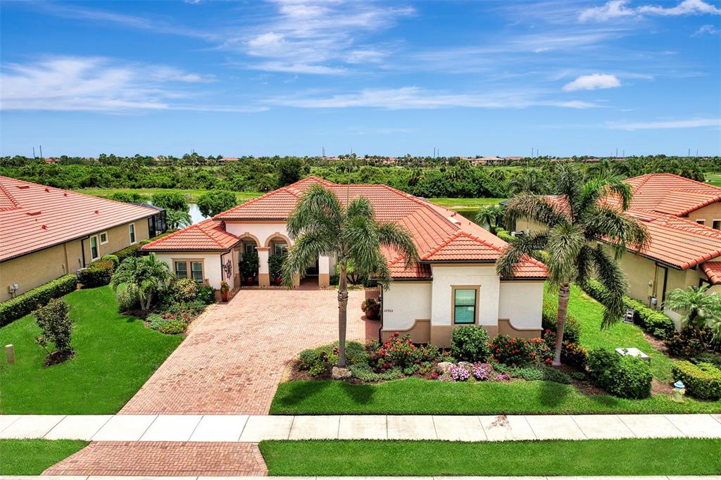 An aerial view of a single-story house with a red tile roof and brick driveway — 10965 BULLRUSH DRIVE, VENICE, FL