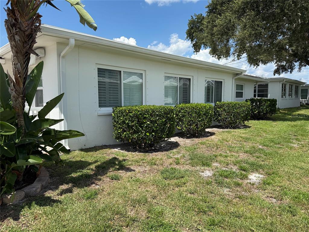 The exterior of a white, single-story building features several windows, manicured shrubs, and a palm tree — 4534 101ST AVENUE N, PINELLAS PARK, FL