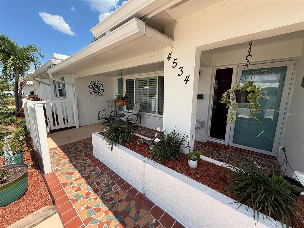 A covered front porch features a tiled walkway, a raised planter bed, and a front door — 4534 101ST AVENUE N, PINELLAS PARK, FL