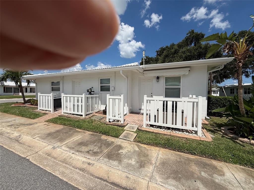 A white single-story building features two entry doors, white picket fences, and brick patios — 4534 101ST AVENUE N, PINELLAS PARK, FL