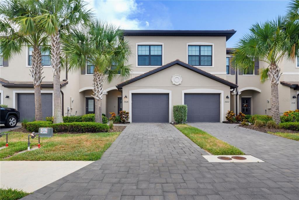 A two-story townhouse exterior features two gray garage doors and a paved driveway — 15126 LYLA TERRACE, LAKEWOOD RANCH, FL