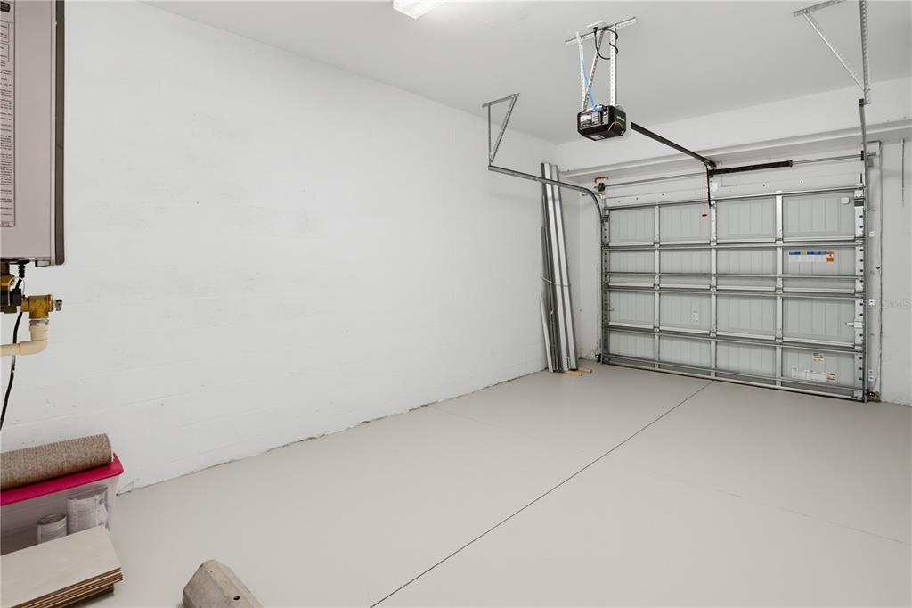 A clean garage with white block walls, a gray floor, and a metal roll-up door — 15126 LYLA TERRACE, LAKEWOOD RANCH, FL