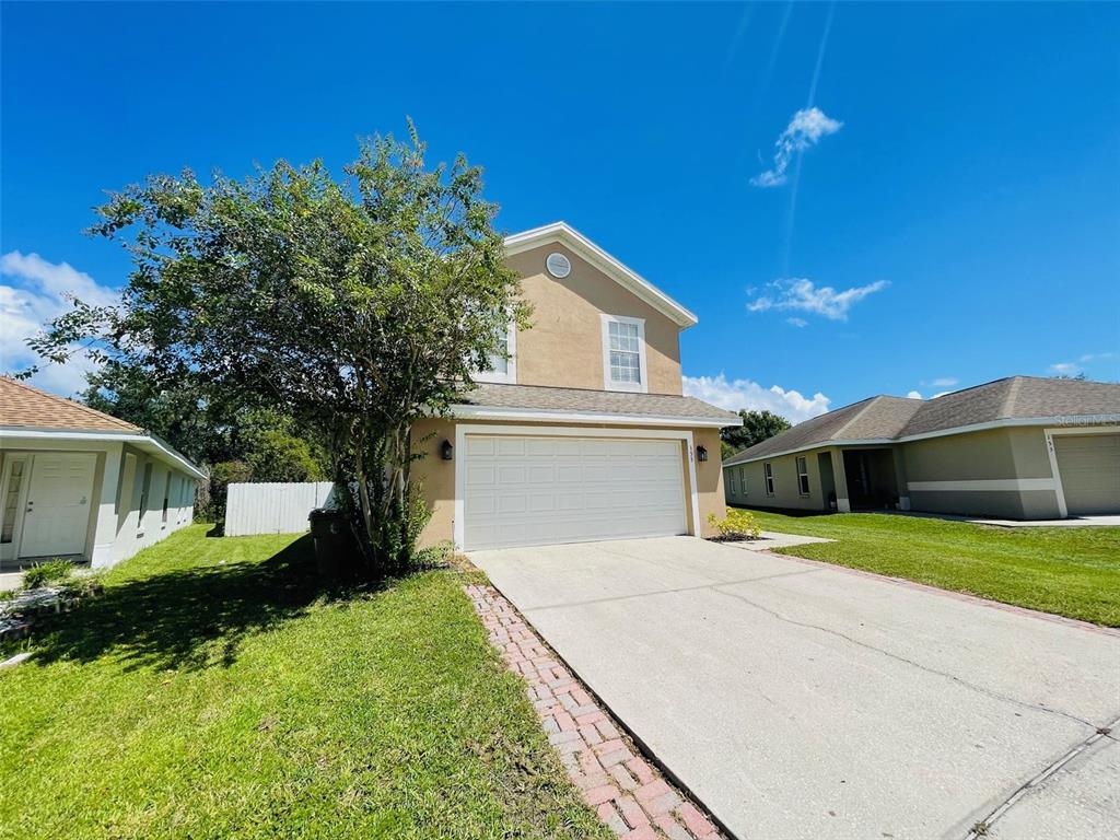 A two-story house with a beige stucco exterior, a two-car garage, and a concrete driveway — 155 OWENSHIRE CIRCLE, KISSIMMEE, FL